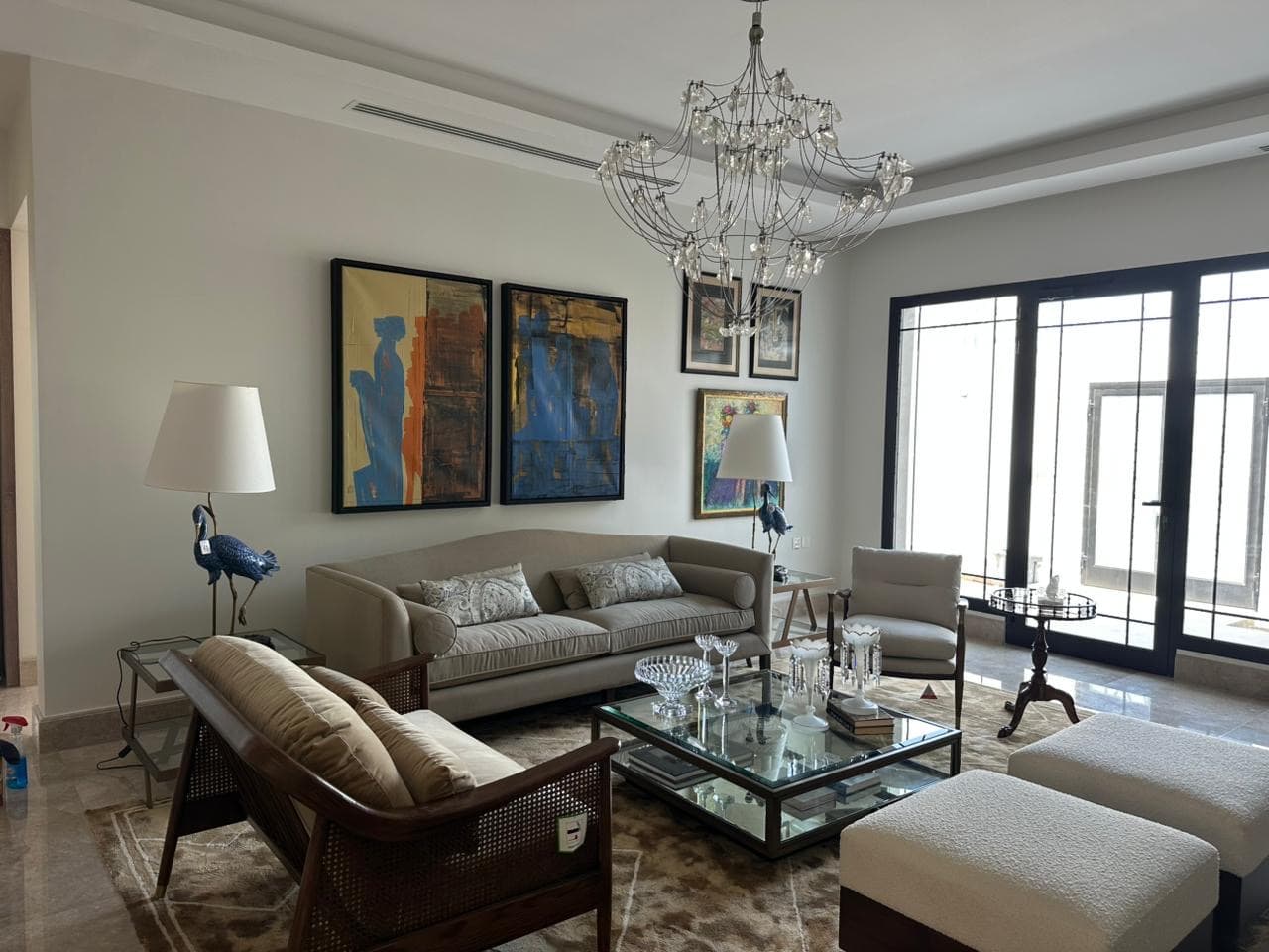 Living room with curated art and a crystal chandelier — private villa fit-out